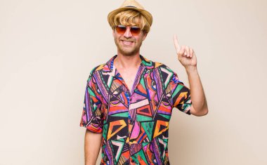 Sarışın, yetişkin gezgin, neşeli ve mutlu bir şekilde gülümseyen, bir eliyle uzayı gösteren