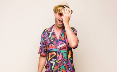 Sarışın, yetişkin gezgin adam gülüyor ve alnına şaplak atıyor. Unuttum ya da aptalca bir hataydı. 