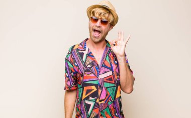 Sarışın, yetişkin, kendini başarılı ve tatmin olmuş hisseden, ağzı açık gülümseyen, elle imza atan biri.