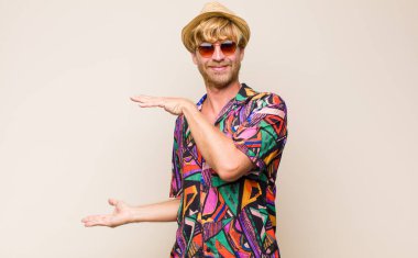 Sarışın, yetişkin bir gezgin, iki eli yandan fotokopi alanında bir nesneyi tutuyor, bir nesneyi gösteriyor, sunuyor ya da reklamını yapıyor.