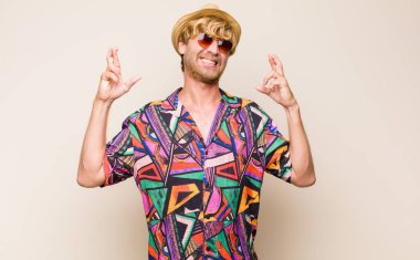 Sarışın, yetişkin gezgin gülümseyerek ve endişeyle iki parmağını çaprazlayarak endişeli ve iyi şanslar diliyor.