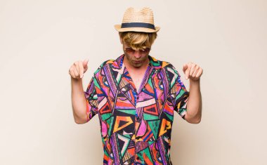 Sarışın, yetişkin, ağzı açık, iki eliyle aşağıya bakan, şaşkın, şaşkın ve şaşkın bakışlı bir gezgin.