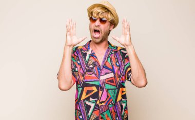 Sarışın, yetişkin bir gezgin ellerini havaya kaldırıp bağırıyor. Öfkeli, sinirli, stresli ve üzgün.