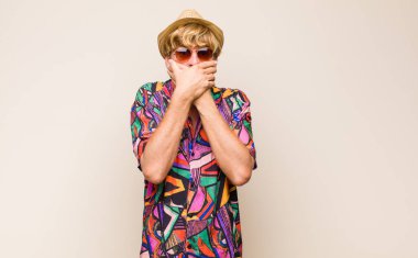 Sarışın, yetişkin bir gezgin şok olmuş, şaşırmış bir ifadeyle elleri ile ağzında dolanıyor, sır saklıyor ya da 