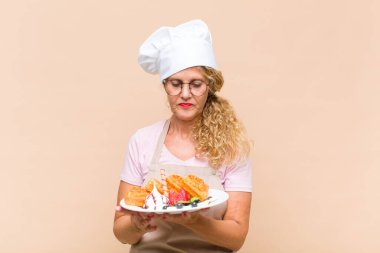 Orta yaşlı fırıncı kadın waffle pişiriyor.