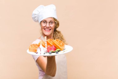 Orta yaşlı fırıncı kadın waffle pişiriyor.