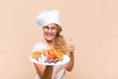 Orta yaşlı fırıncı kadın waffle pişiriyor.