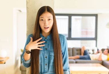 Genç, güzel Asyalı kadın şok olmuş, şaşırmış ve şaşırmış hissediyor, elleri göğsünde ve ağzı açık, kim olduğumu söylüyor, ben mi??