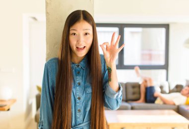 Genç, güzel Asyalı kadın kendini başarılı ve tatmin olmuş hissediyor, ağzı açık gülümsüyor, elle imza atıyor.