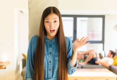 Genç, güzel Asyalı bir kadın mutlu, şaşırmış ve neşeli, pozitif bir tavırla gülümsüyor, bir çözüm ya da fikri fark ediyor.