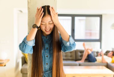 Genç, güzel Asyalı bir kadın stresli ve hayal kırıklığına uğramış hissediyor. Yumruk yumruğa, yorgun, mutsuz ve migren ağrısı çekiyor.