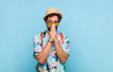 Genç sakallı turist endişeli, umutlu ve dindar hissediyor, avuç içleriyle inançla dua ediyor, af diliyor.