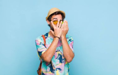 Genç sakallı turist korkmuş ya da utanmış hissediyor, gözleri yarı kapalı ya da elleri kapalı gözetliyor.