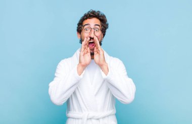 Banyo bornozu giyen genç sakallı adam mutlu, heyecanlı ve pozitif hissediyordu. Elleri ağızın yanında bağırarak bağırıyordu.