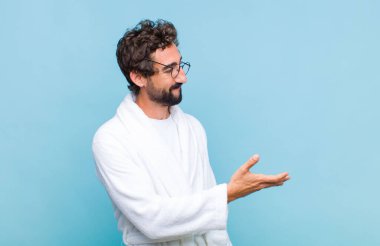 Genç sakallı adam banyo cübbesi giyiyor gülümsüyor, seni selamlıyor ve başarılı bir anlaşma için el sıkışmayı teklif ediyor, işbirliği konsepti.
