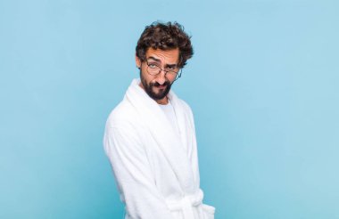 Banyo bornozu giyen genç sakallı adam gururlu, kendinden emin, havalı, küstah, güler yüzlü, başarılı hissediyor.