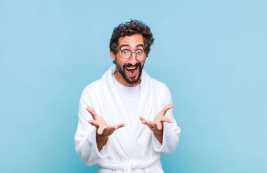 Banyo bornozu giyen genç sakallı adam kendini mutlu, şaşkın, şanslı ve şaşırmış hissediyor. İnanılmaz!