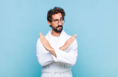 Banyo bornozu giymiş genç sakallı adam tavrından rahatsız ve bıkkın görünüyor, yeter artık! Eller önde çapraz, durmanı söylüyor.