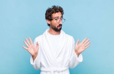 Banyo bornozu giymiş genç sakallı adam gergin, endişeli ve endişeli görünüyor, benim hatam olmadığını söylüyor, yoksa ben yapmadım. 