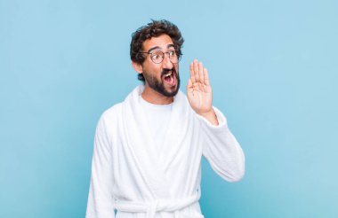 Banyo bornozu giymiş genç sakallı adam öfkeyle ve yüksek sesle bağırarak kenardaki boşluğu kopyalamasını söylüyor.