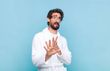 Banyo bornozu giymiş genç sakallı bir adam tiksinti ve mide bulantısı hissediyor. Pis kokan ya da kötü kokan bir şeyden kaçıyor ve iğrenç diyor.