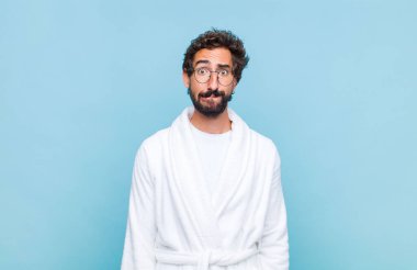 Banyo bornozu giyen genç sakallı adam hangi seçeneği seçeceğine karar veremiyor, bilgisiz, kafası karışık ve kararsız hissediyor.