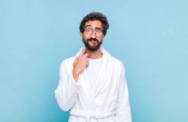 Banyo bornozu giyen genç sakallı adam stresli, hayal kırıklığına uğramış ve yorgun hissediyordu. Endişeli, sıkıntılı bir bakışla boynunu ovuyordu.