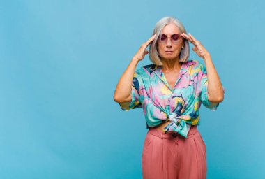 Orta yaşlı, havalı bir kadın. Yoğunlaşmış, düşünceli ve ilham verici görünüyor. Beyin fırtınası yapıyor ve hayal kuruyor.