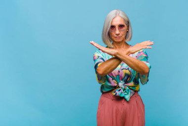 Orta yaşlı, havalı bir kadın senin bu tavırlarından rahatsız ve bıkkın görünüyor. Yeter artık! Eller önde çapraz, durmanı söylüyor.