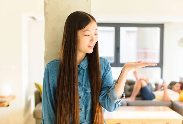 幸せそうなアジア系の若い女性が気軽に笑顔で手に持っている物や概念を探し — ストック写真