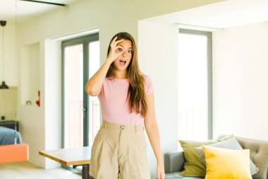 Genç, güzel bir kadın şaşkın, şaşırmış ve şaşırmış hissediyor. Elinde şaşkın, inançsız bir bakışla gözlük tutuyor.