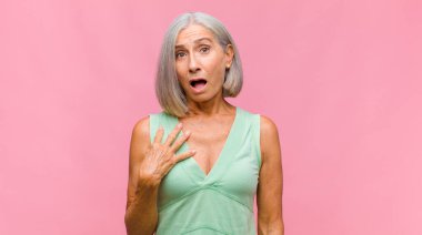 Orta yaşlı güzel bir kadın neşeyle gülümsüyor, mutlu, tatmin olmuş ve rahatlamış hissediyor, kollarını kavuşturup yan tarafa bakıyor.