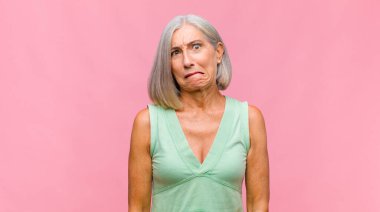 Orta yaşlı, güzel bir kadın şok olmuş ve şaşırmış hissediyor. Şaşırmış ve ağzı açık bir şekilde hayranlıkla yukarı bakıyor.