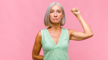 Orta yaşlı, güzel bir kadın dehşete kapılmış ve şok olmuş hissediyor. Bir hata yüzünden ellerini kaldırıyor ve panikliyor.