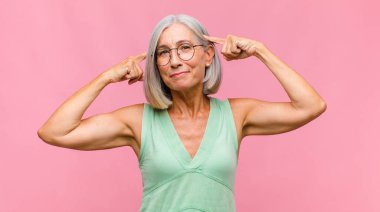 Orta yaşlı, güzel bir kadın mutlu bir şekilde gülümsüyor ve hayal kuruyor ya da şüphe ediyor.