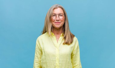 Orta yaşlı, güzel bir kadın mutlu ve şapşal görünüyor. Geniş, eğlenceli, kaçık bir gülüşü ve açık gözleri var.