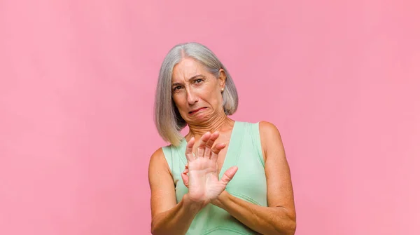 middle age pretty woman screaming in panic or anger, shocked, terrified or furious, with hands next to head