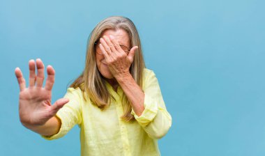 Orta yaşlı, güzel bir kadın iğreniyor, kötü ve nahoş bir koku duymamak için burnunu tutuyor.