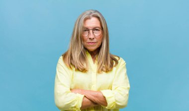 Orta yaşlı, güzel bir kadın bilgisiz ve kafası karışık, bir çözüm düşünüyor, eli kalçasında, diğeri kafasında, dikiz aynasından.