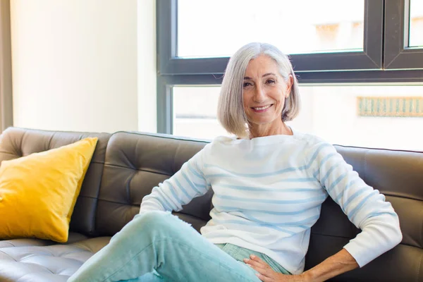 middle age pretty woman smiling to camera with crossed arms and a happy, confident, satisfied expression, lateral view