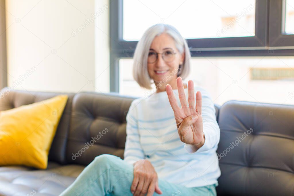middle age pretty woman smiling and looking friendly, showing number four or fourth with hand forward, counting down