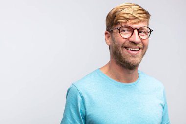 Genç sarışın adam mutlu ve gülümsüyor. tatmin edici ifade