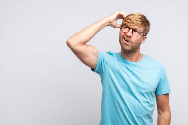 Genç sarışın adam düşünme ya da şüphe dolu bir ifade