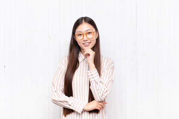 Azji Młoda Kobieta Wygląda Szczęśliwy Uśmiechnięty Ręki Brodzie Zastanawiasz Się — Zdjęcie stockowe