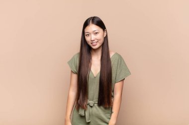 Asyalı genç kadın gururlu, kendinden emin, havalı, küstah ve kibirli görünüyor, gülümsüyor, başarılı hissediyor.