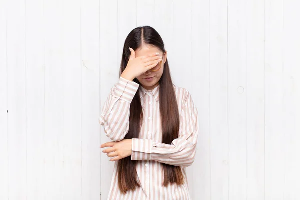 アジア系の若い女性は顔を手で覆い — ストック写真