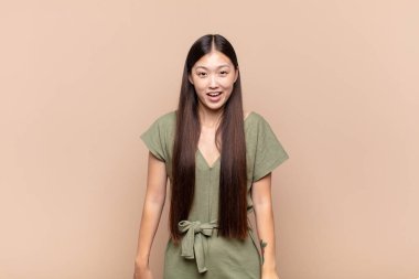 Asyalı genç kadın mutlu ve hoş bir şekilde şaşırmış görünüyor. Büyülenmiş ve şok olmuş bir ifadeyle heyecanlanıyor.