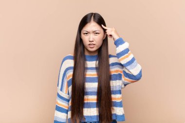 Asyalı genç kadın şaşkın ve şaşkın hissediyor. Deli, deli ya da aklını kaçırmış olduğunu gösteriyor.