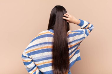 Asyalı genç kadın düşünüyor ya da şüphe ediyor, kafasını kaşıyor, kafası karışık ve kafası karışık hissediyor, arkaya ya da arkaya bakıyor.