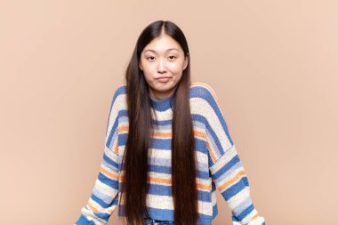 asian young woman feeling clueless and confused, having no idea, absolutely puzzled with a dumb or foolish look